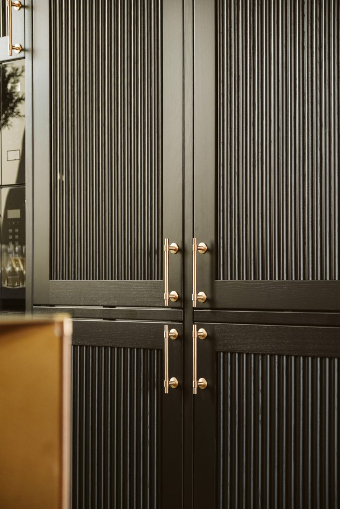Närbild av svarta räfflade skåpsdörrar hos Banken med eleganta handtag i mässing.